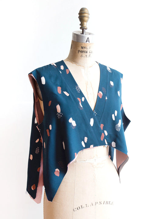 Felix Dress in teal abstract print on dress form, crossover V-neckline with neckband attached and pink lining visible