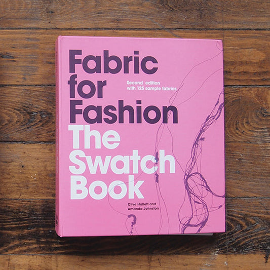 Fabric for Fashion: The Swatch Book second edition by Clive Hallett and Amanda Johnston, pink cover on wooden surface
