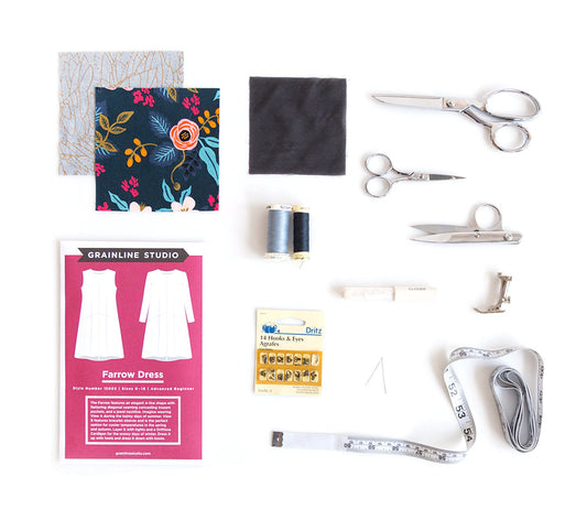 Farrow Dress sewing supplies: pattern envelope, fabric swatches, interfacing, thread, scissors, hooks and eyes, tape measure