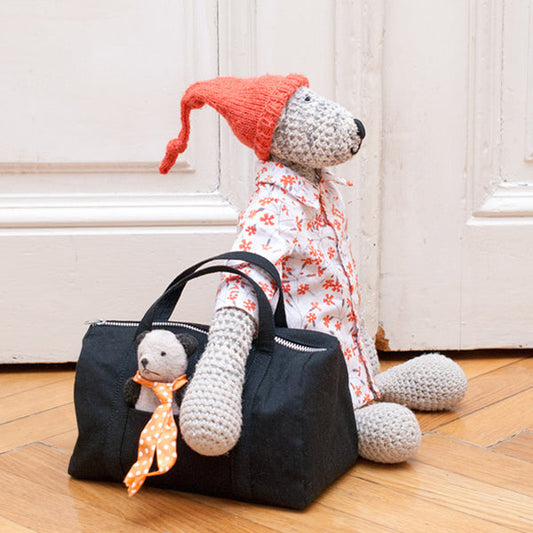 Miniature Portside Duffle in black cotton twill, styled with knitted bear in red hat and floral dress on wood floor