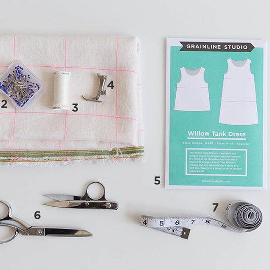 Willow Tank Dress flat lay with pattern envelope, windowpane linen, pins, thread, presser foot, scissors, and measuring tape