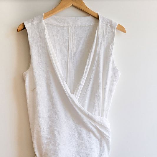 White wrap top with draped crossover front and sleeveless design on wooden hanger, showing Hadley Top modification