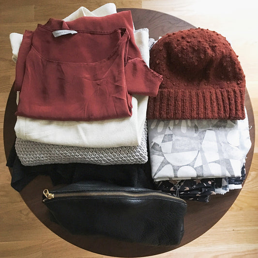 Travel capsule: rust blouse, cream sweater, gray knit, rust bobble beanie, printed fabrics, and black leather pouch