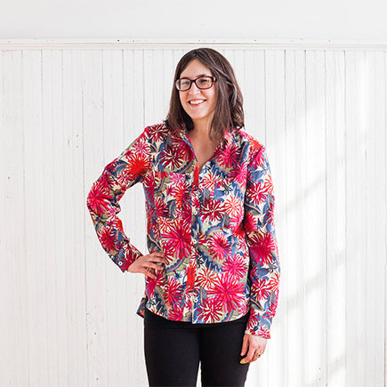 Smiling woman wearing an Archer Button-Up in a bold red and pink floral Liberty Lawn print, paired with black pants