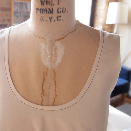Close-up of a bias-faced scoop neckline on a sleeveless top on a dress form, showing flat binding stitched to the inside
