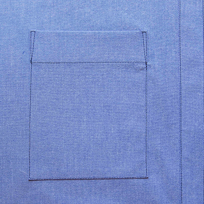 Close-up of a blue chambray Archer Button-Up chest pocket with folded and topstitched header, sewn onto the shirt front