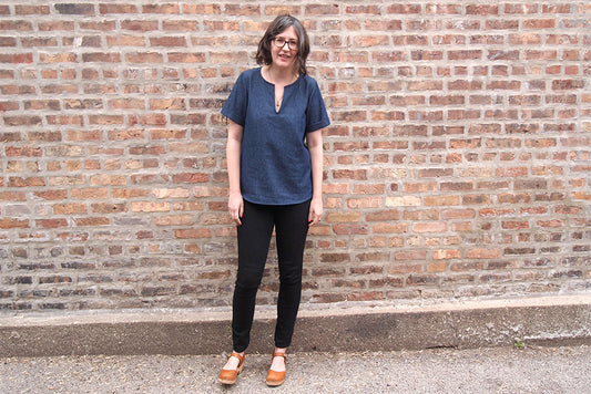 Woman wearing a Scout Tee variation in indigo denim with short sleeves and notched neckline, paired with black pants