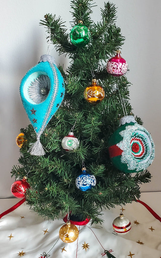 Small Christmas tree decorated with handmade felt and vintage-style glass ornaments in turquoise, pink, red, gold, and green