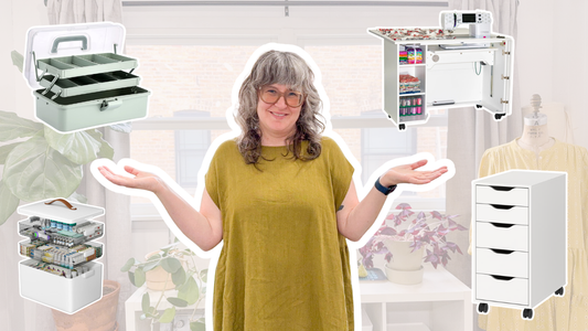 Jen Beeman in mustard dress and glasses, hands raised, surrounded by sewing room storage solutions for Making Space to Make