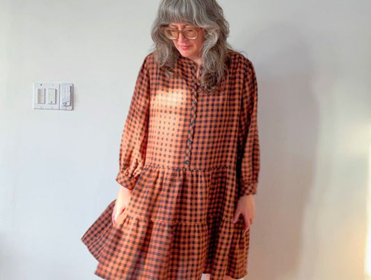 Jen Beeman in rust and black gingham linen Poppy Dress with long gathered sleeves, button-front placket and tiered skirt