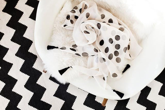 DIY scarf tutorial: cream polka dot silk chiffon scarf with black tassels, draped on Eames chair on chevron rug