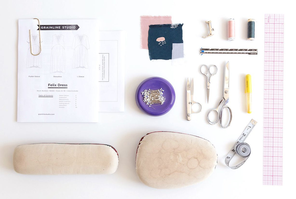 Flat lay of Felix Dress sewing supplies including pattern, fabric swatches, thread, pins, scissors, and rulers
