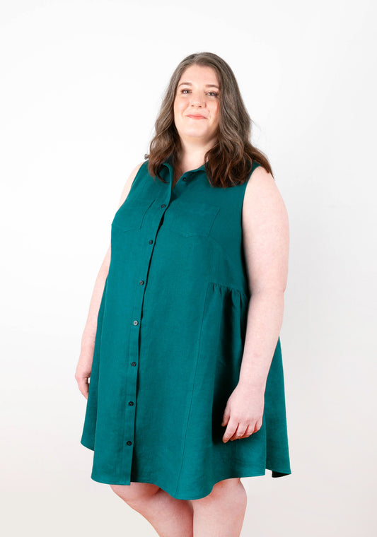 Model: Size 20, 5'5" | Angled front view of Alder Shirtdress View B in teal linen, showing collar, pockets, and gathered side skirt.