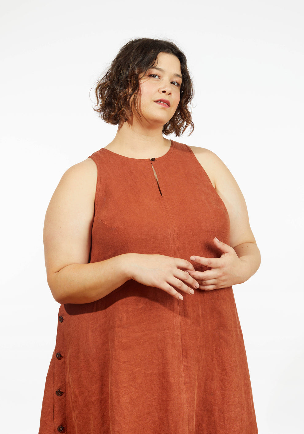 Close up of Austin Dress in rust linen showing neckline detail and sleeveless bodice on model.