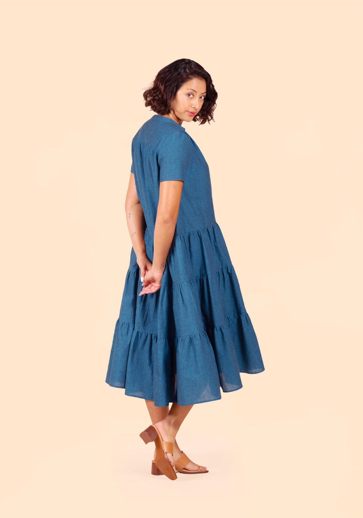 Model turned slightly in Poppy Dress View C with short sleeves and full gathered skirt in motion.