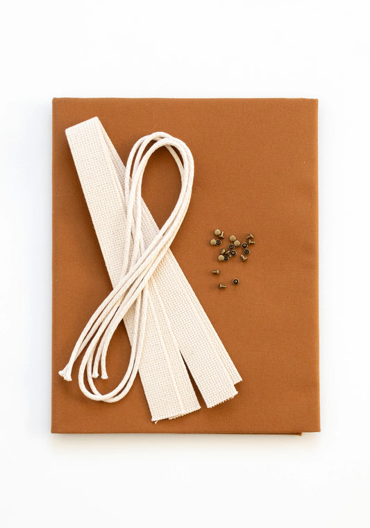 Flatlay of Town Bag fabric kit in toffee with cotton webbing, drawstring cord, and antique brass rivets.