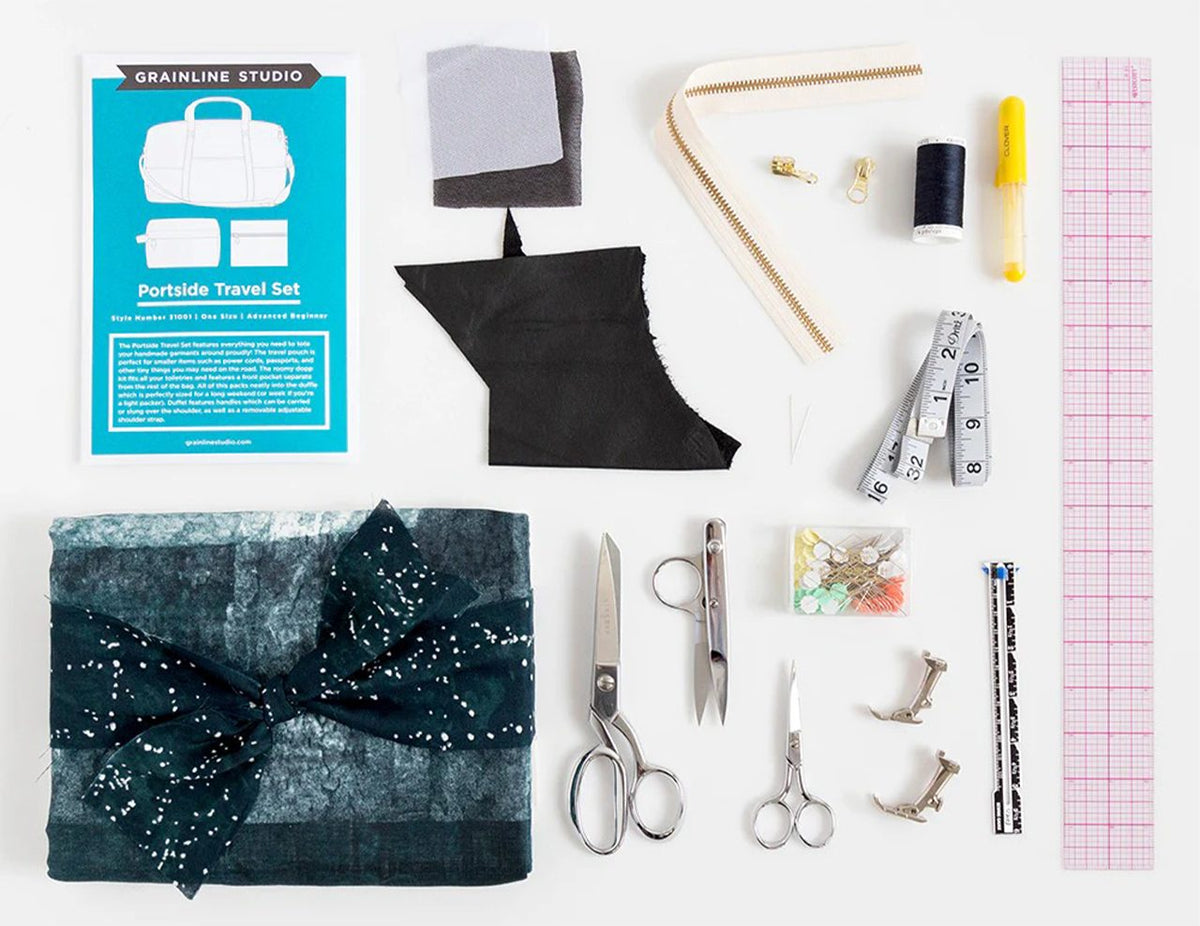 Portside pattern envelope with fabrics, interfacing, gold zipper, thread, zipper pulls, measuring tape, rulers, scissors, and pins