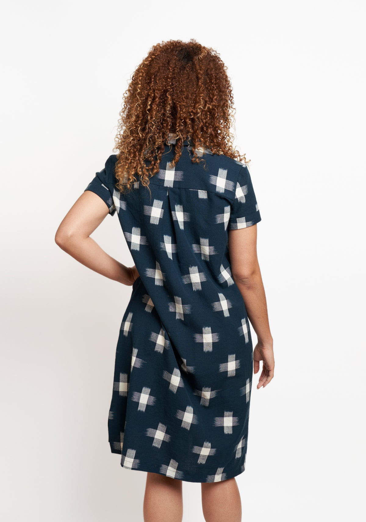 Back view of navy Augusta Dress with short sleeves and white cross pattern, showing box pleat at yoke.