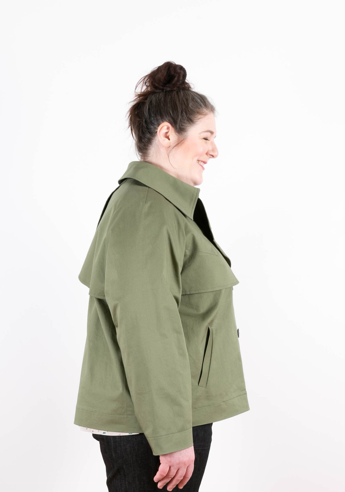 Side view of green Cortland Trench on model, smiling and looking down.