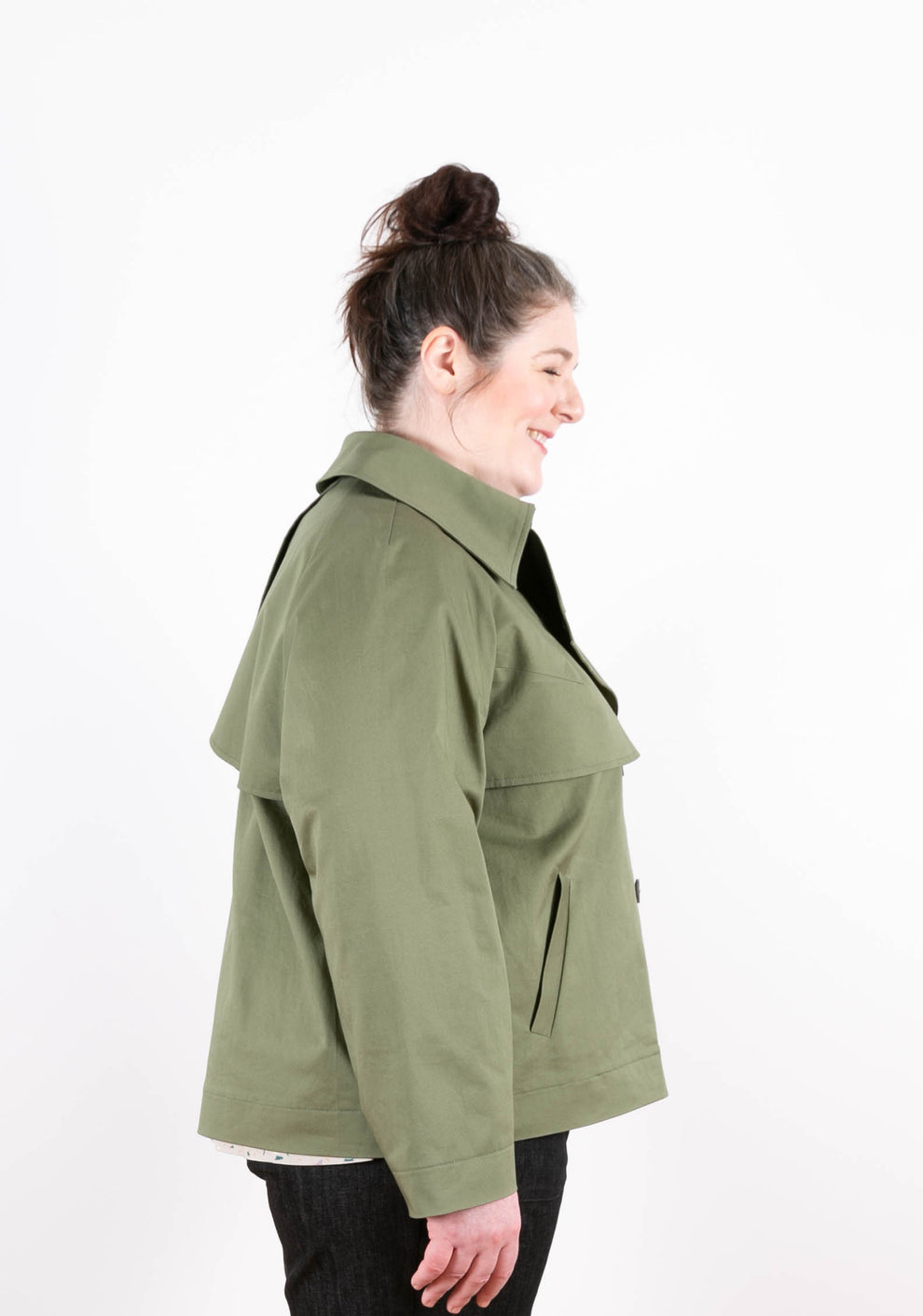 Side view of green Cortland Trench on model, smiling and looking down.