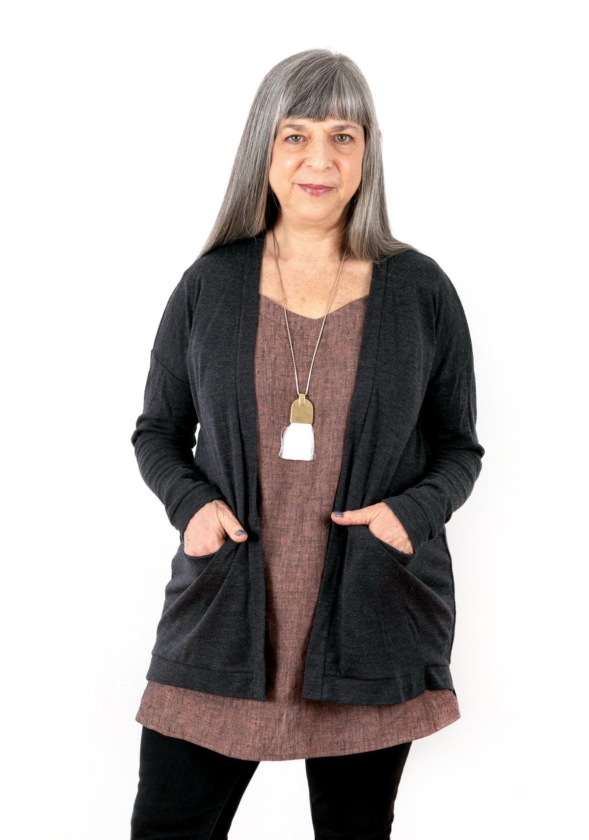 Model: Size 12, 5'3" | Front view of charcoal Driftless Cardigan layered over Uniform Tunic, modeled with hands in pockets.