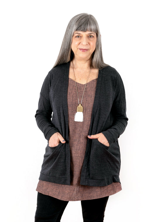 Model: Size 12, 5'3" | Front view of charcoal Driftless Cardigan layered over Uniform Tunic, modeled with hands in pockets.