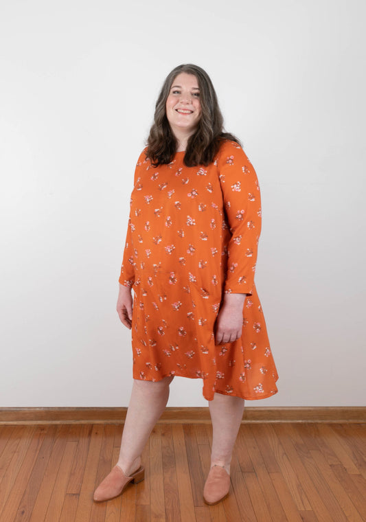 Model: Size 20, 5'5"| Full front view of orange floral Farrow Dress in size 14-32 with long sleeves and subtle A-line shape.
