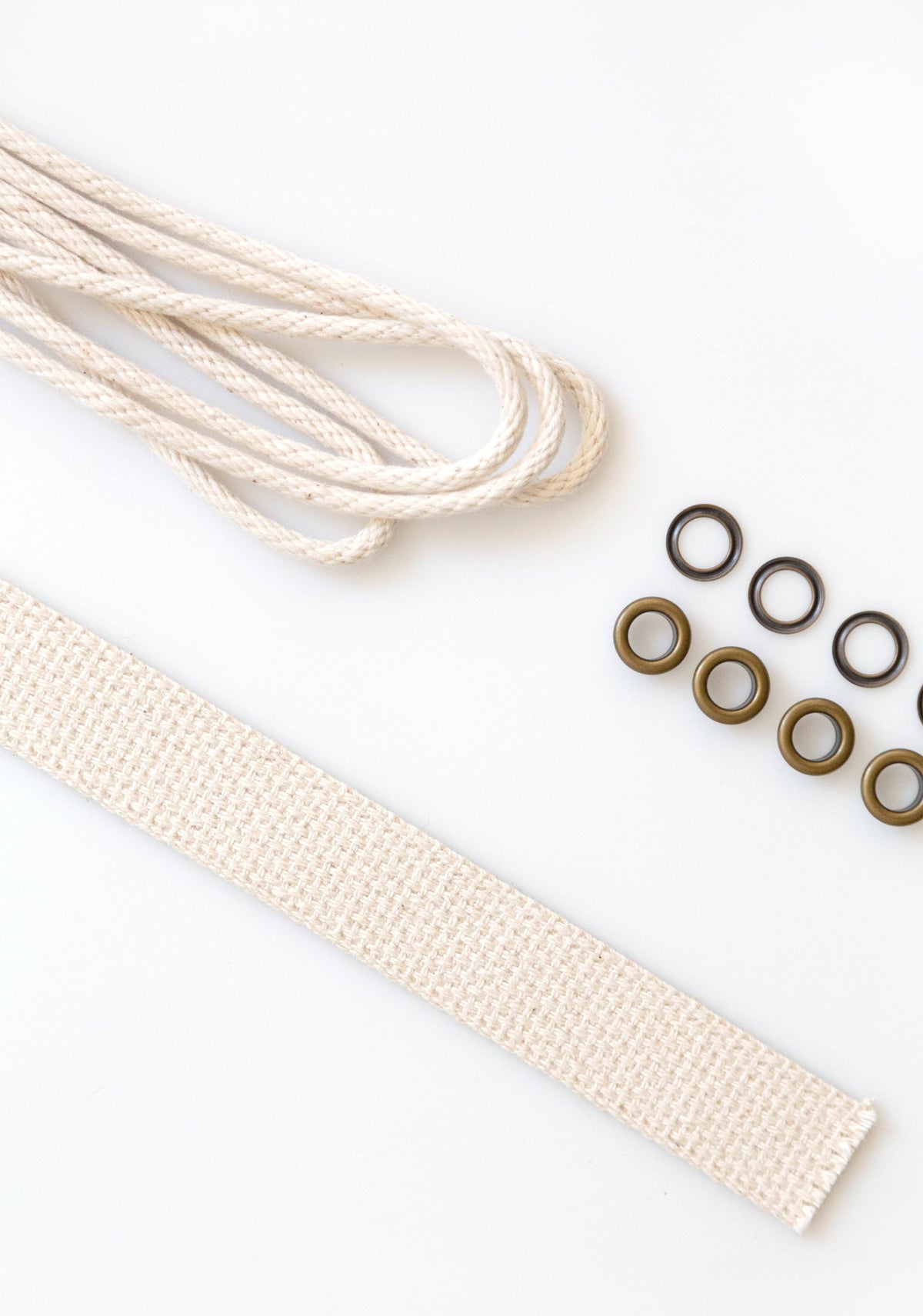 Angled view of Field Bag notions kit with natural cotton webbing, cord, and brass grommets on white surface.