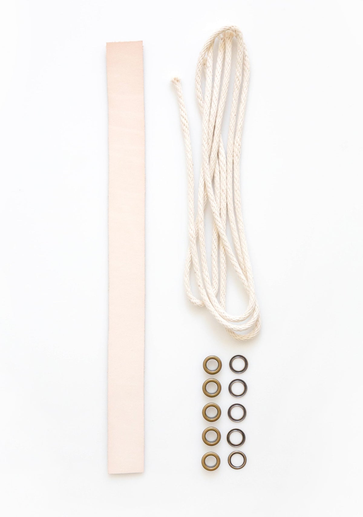 Model: Leather Handle | Flatlay of Field Bag notions kit with natural leather strap, drawstring cord, and brass grommets.