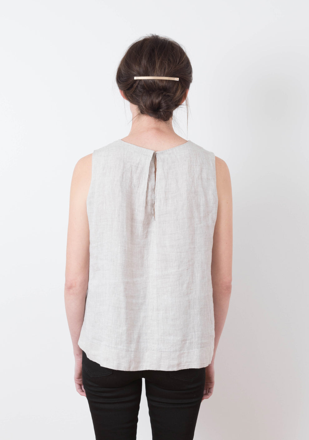 Back view of sleeveless Hadley Top in light linen with pleat detail, worn by model.