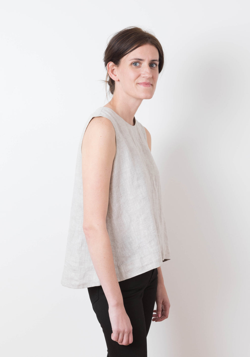 Side view of sleeveless Hadley Top in light linen showing A-line silhouette, worn by model.