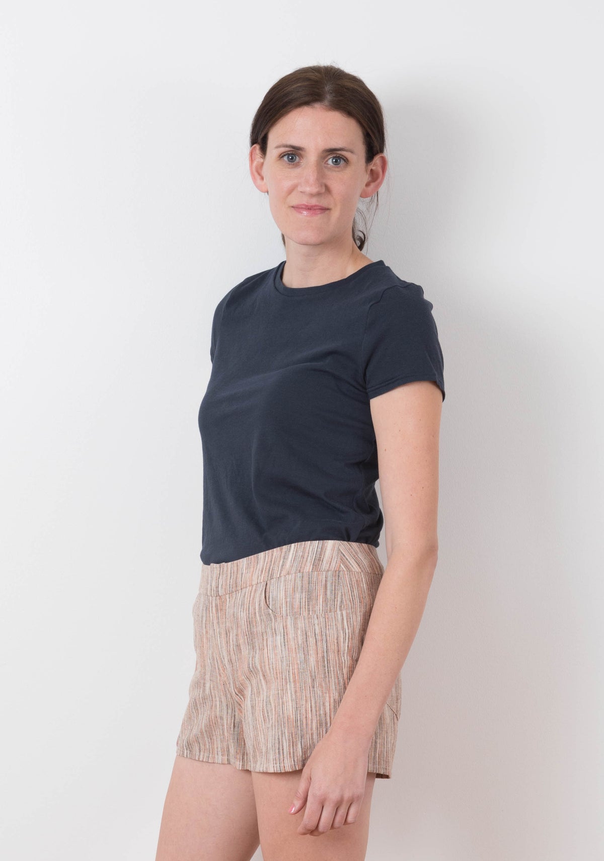 Side view of model in striped Grainline Maritime Shorts and navy t-shirt.