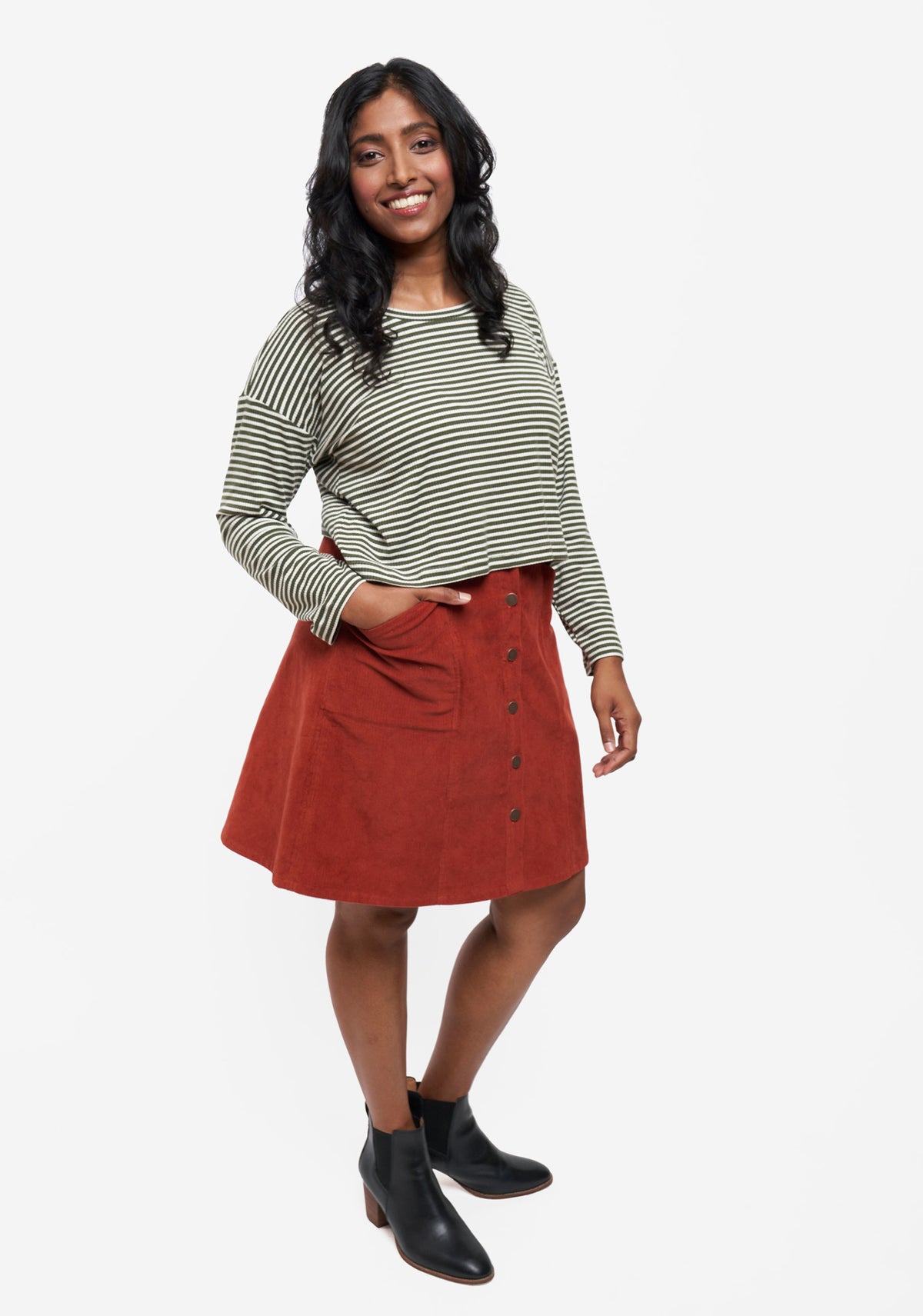 Angled front view of Reed Skirt in rust corduroy styled with striped top and black ankle boots.
