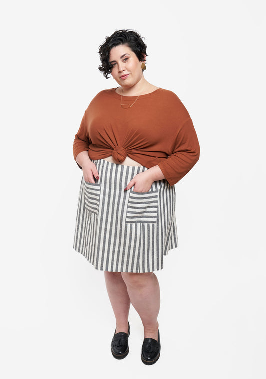 Model: Size 28, 5'7" | Front view of Reed Skirt in striped fabric with patch pockets, worn with rust top.