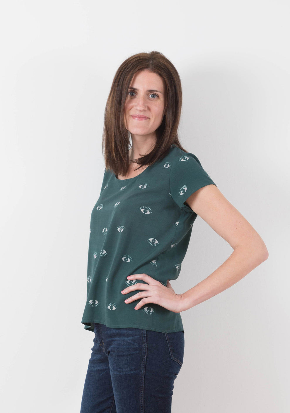 Model wearing green Scout Tee with eye print in side view, hand on hip.