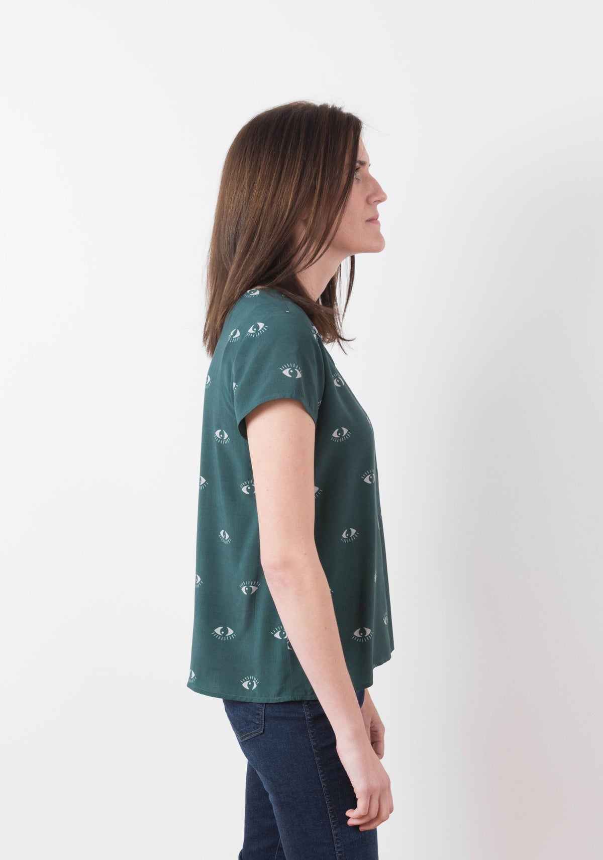 Model wearing green Scout Tee with eye print in side view, facing left.