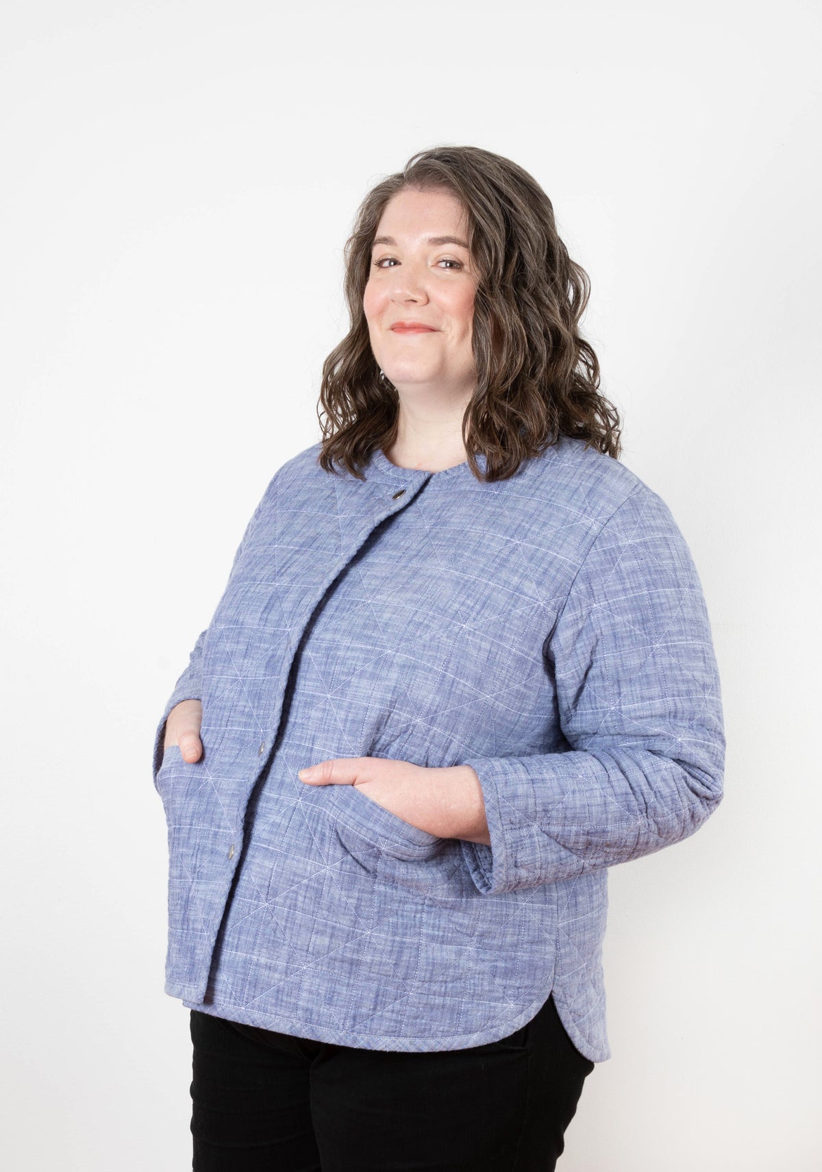 Side view of model wearing Tamarack Jacket in blue chambray, hands in pockets with snap front detail.