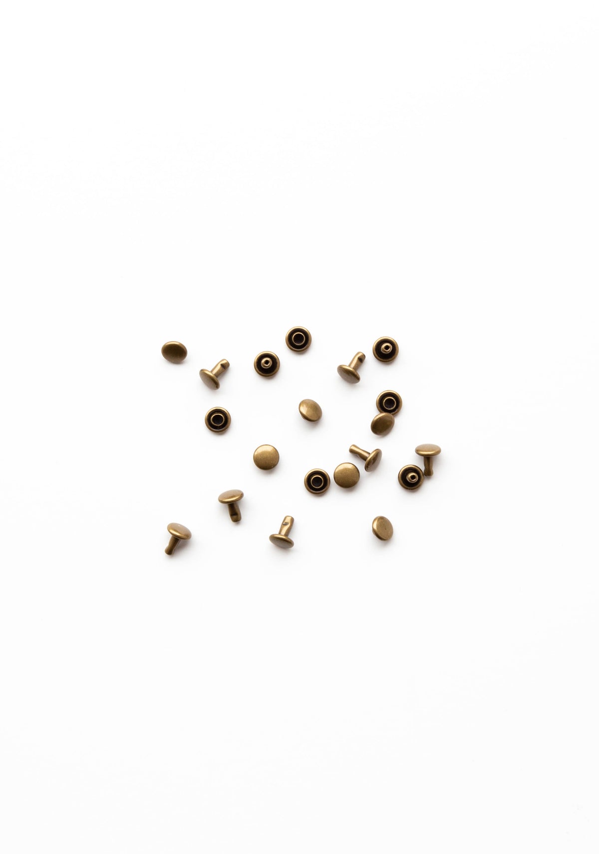 Flatlay of antique brass rivets for the Town Bag sewing pattern on a clean white background.