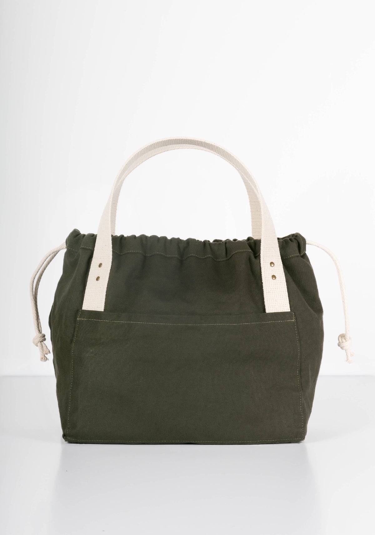 Front view of green canvas Town Bag with white handles and drawstring closed.