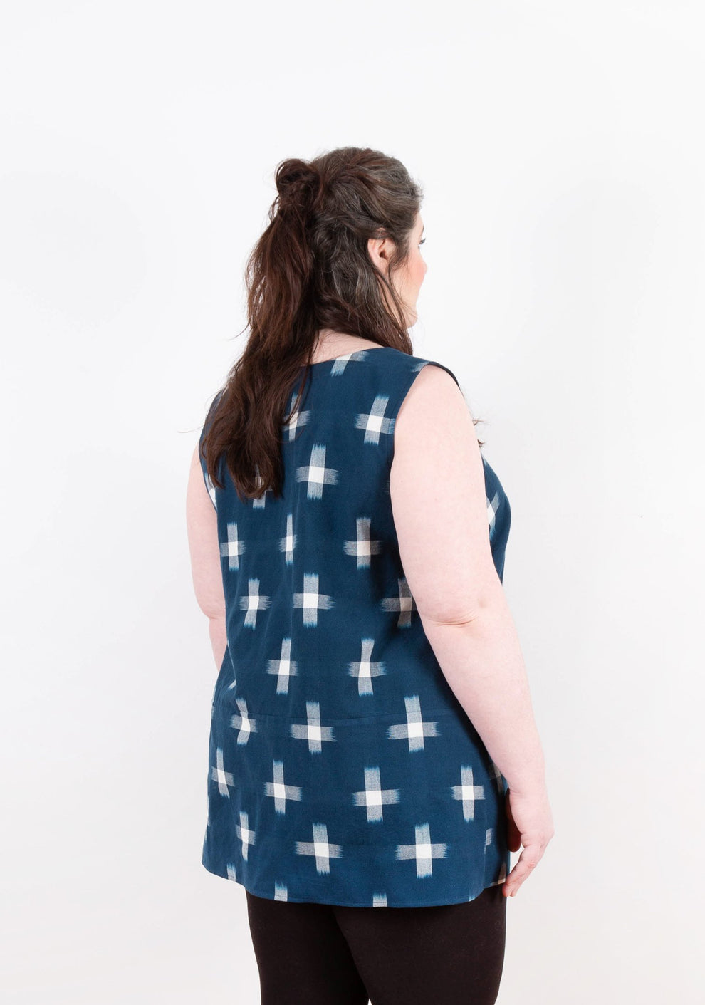 Three-quarter back view of sleeveless navy Uniform Tunic with ikat print and curved hem.
